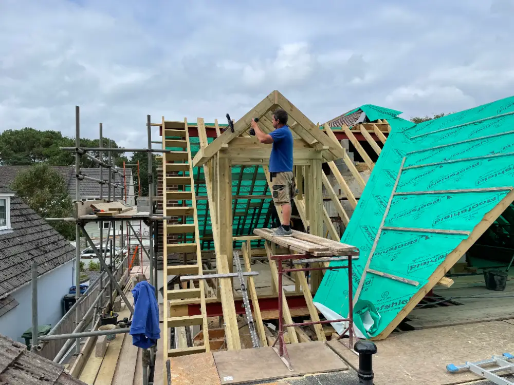One of our carpenters framing a new loft dormer from scaffolding, with breathable membrane over the new rafters