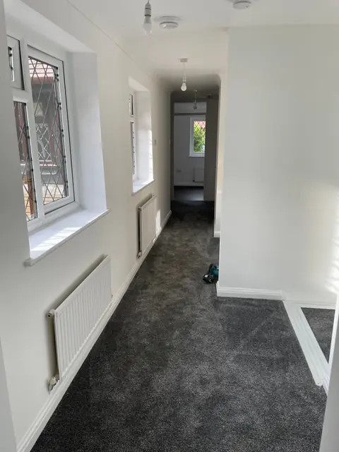 A long, bright corridor with grey carpet and leaded windows