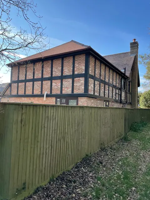 The new two storey extension seen over the side fence, with black timber framing to match the house