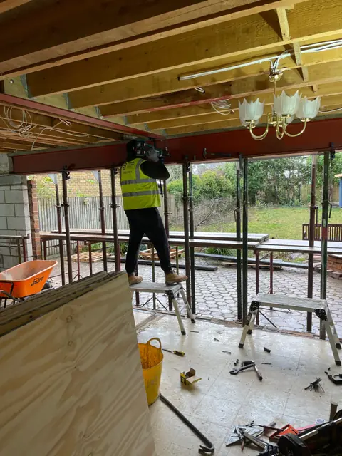 One of our team fixing the new steel beam across the back of the house, with props along the opening