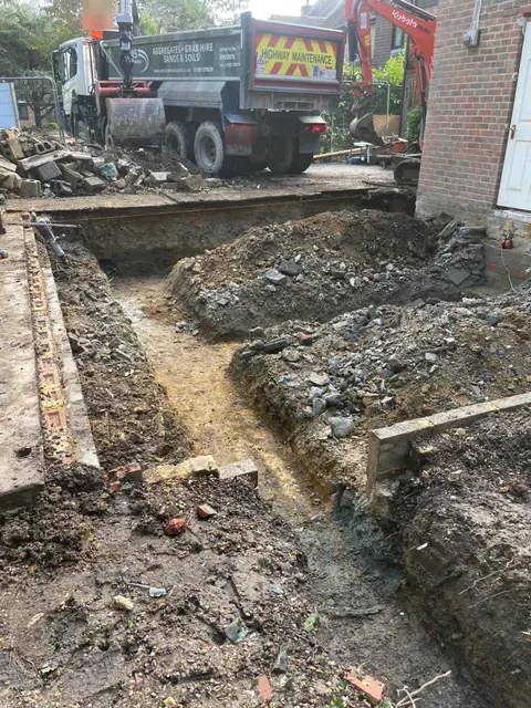 Foundations being dug beside the house, with a grab lorry and a mini digger taking away the spoil