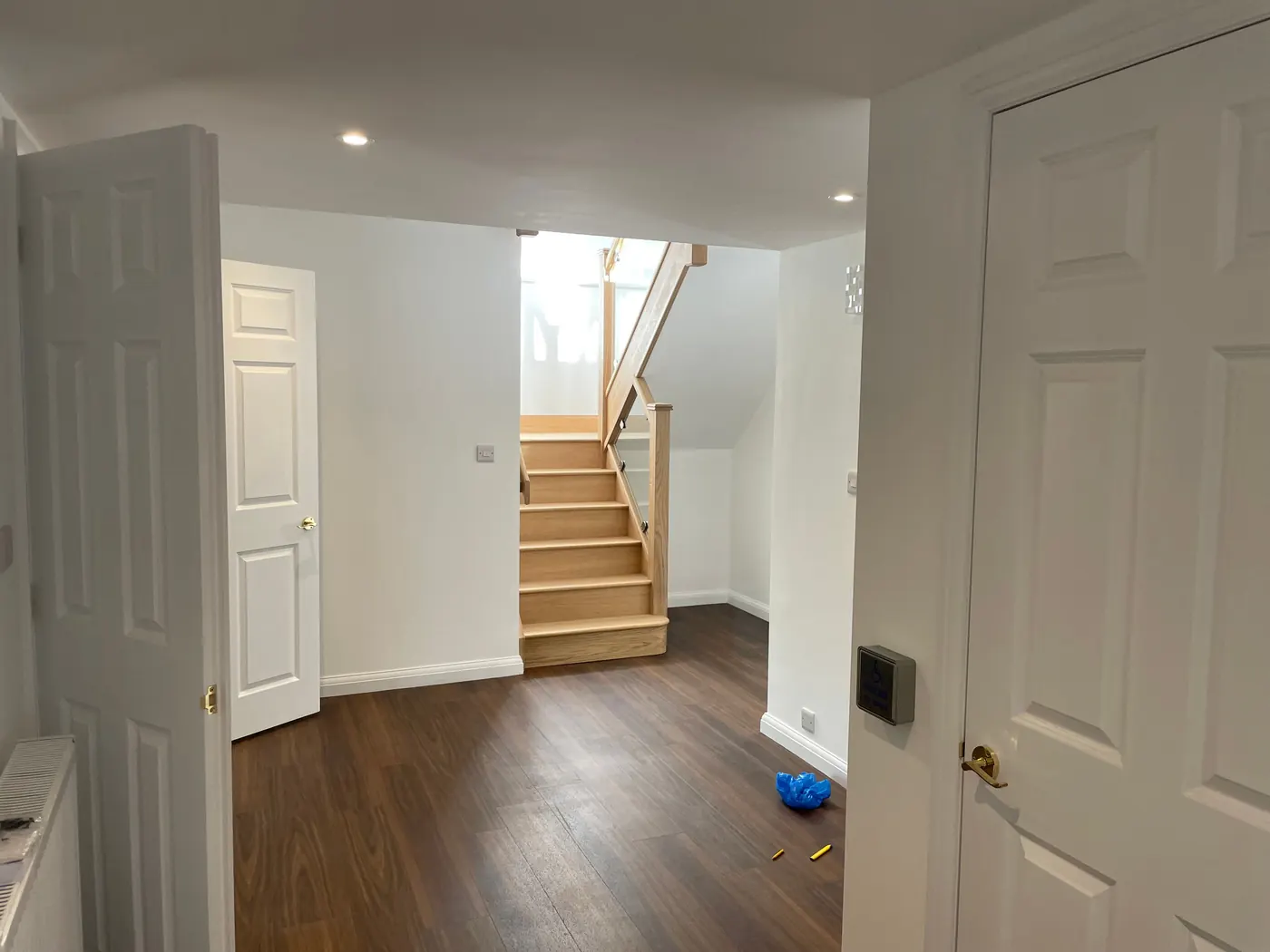 A hallway with wide doorways and the oak staircase