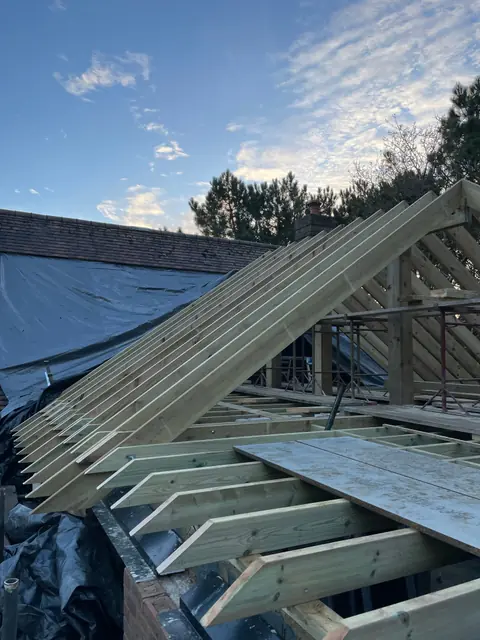Rafters fixed up to the ridge of the new roof, with the old roof slope sheeted alongside