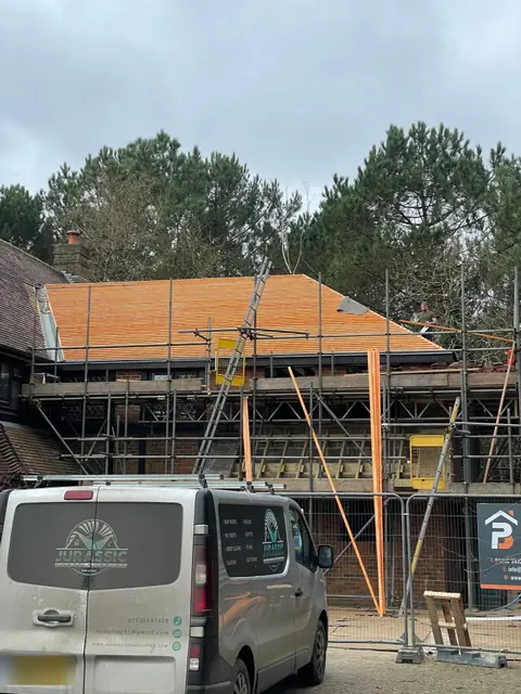Roofing battens across the new roof, with scaffolding around the house and a roofer’s van on the drive