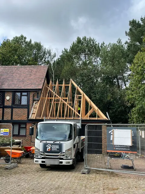 New timber roof framing going up above the garage, with our truck on the drive and site fencing in place