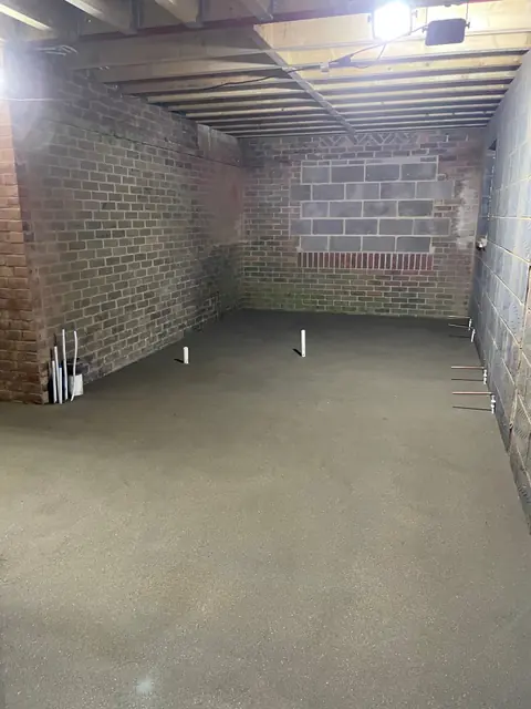 A long room in the extension with a new screed floor and pipework set into it