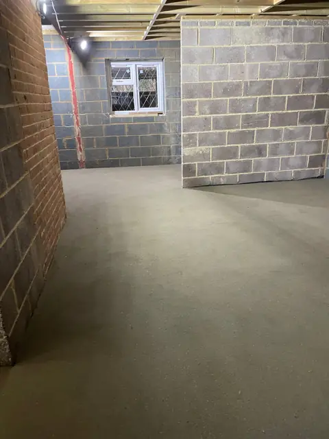 A room in the extension with a fresh screed floor and blockwork walls