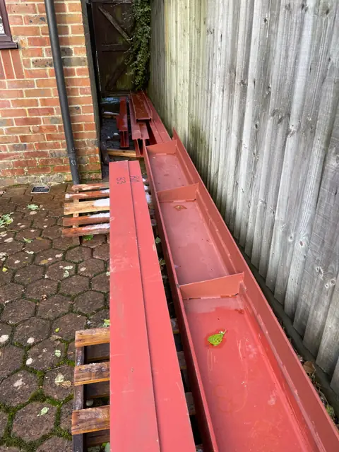 Red steel beams delivered and stacked along the side passage