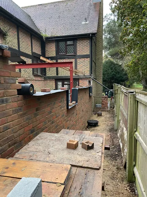 A red steel frame set on the new brick walls along the side of the house