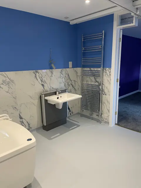 A wet room basin, a heated towel rail and the doorway through to the bedroom