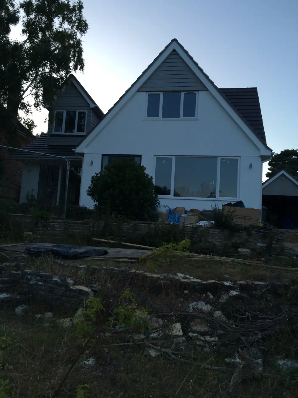 Newly rendered chalet with grey cladding and new windows before landscaping