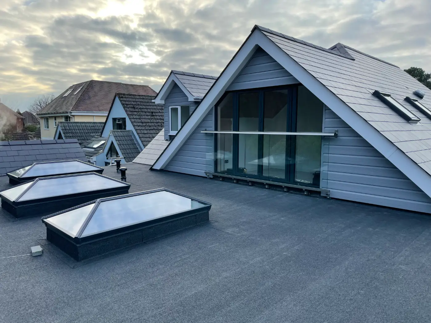Flat roof terrace with three roof lanterns beside a new glazed gable