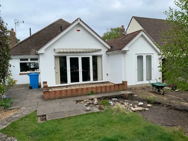 Rear of the house before the extension, with patio doors under an awning and a small paved patio