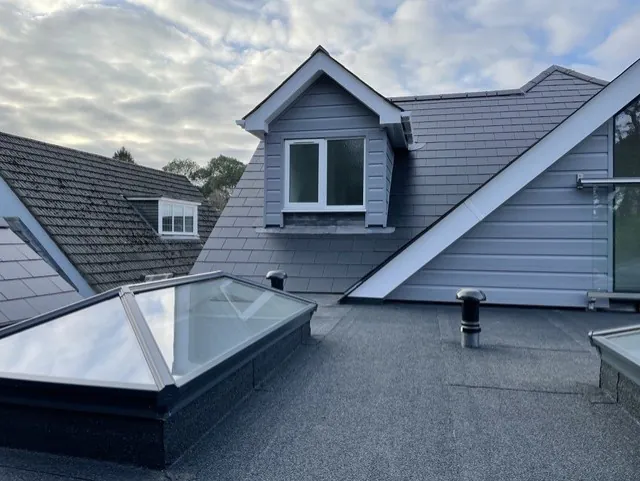 Grey clad dormer with a white window on the rear roof slope, above a pitched roof lantern on the flat roof